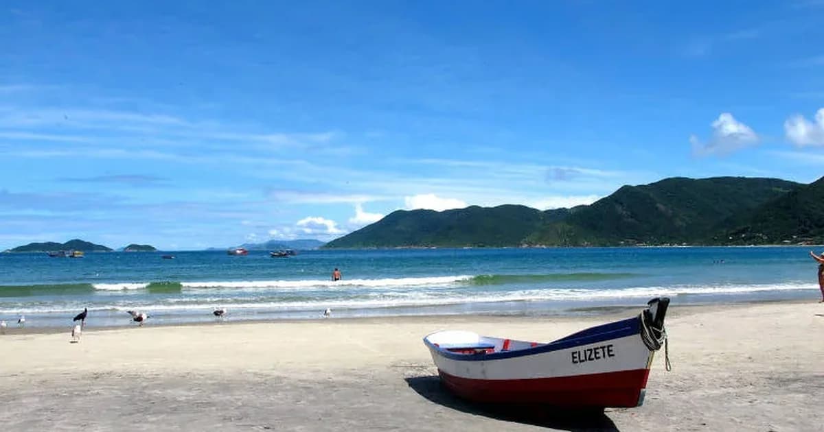 Barco de pesca na praia do Rio Tavares com o mar e as montanhas do Sul da Ilha ao fundo, Florianópolis